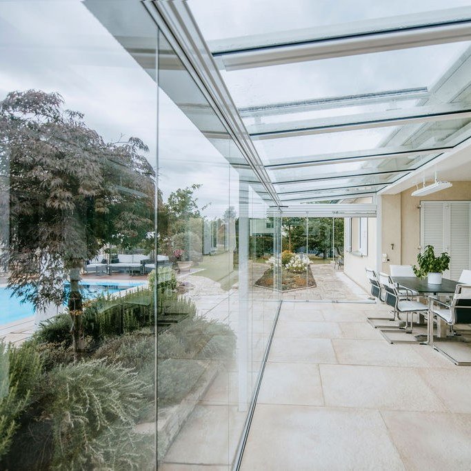 Sommergarten mit Glasdach und COVER Schiebe-Drehverglasung, Essplatz und Blick auf den Pool